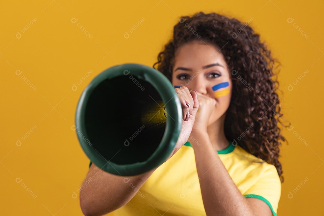 Linda mulher jovem morena segurando bandeira do brasil cabelo cacheado sobre fundo isolado amarelo