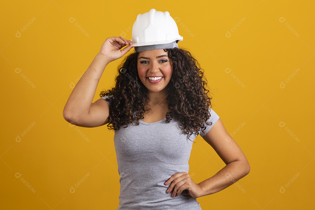Linda mulher jovem garota cabelo cacheado engenheira usando capacete branco fundo isolado amarelo