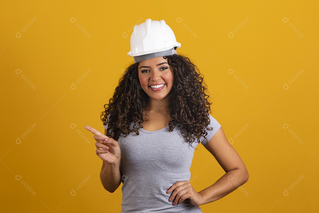 Linda mulher jovem garota cabelo cacheado engenheira usando capacete branco fundo isolado amarelo