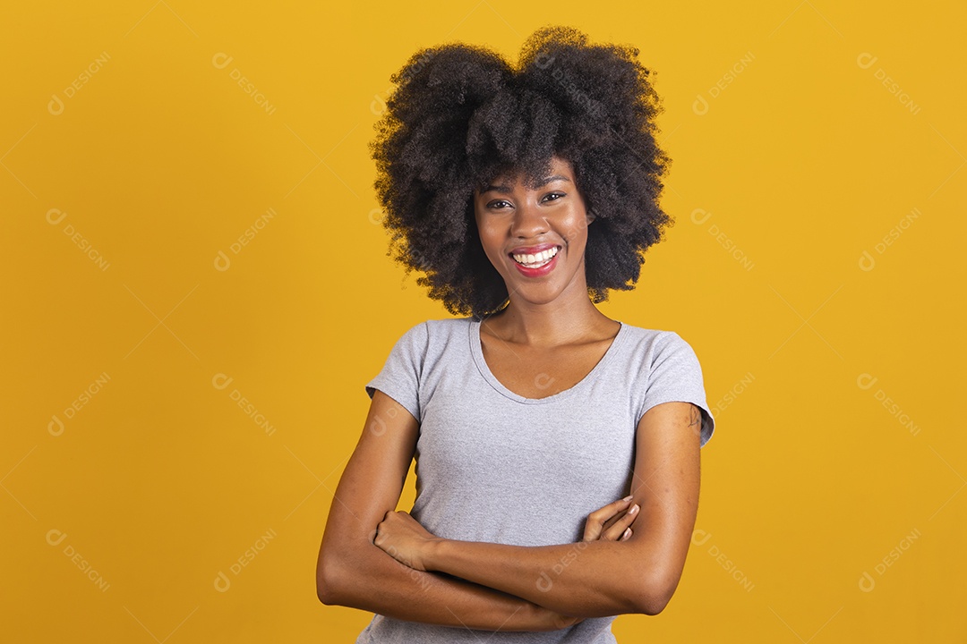 Mulher jovem morena cabelo afro braços cruzados sobre fundo isolado amarelo