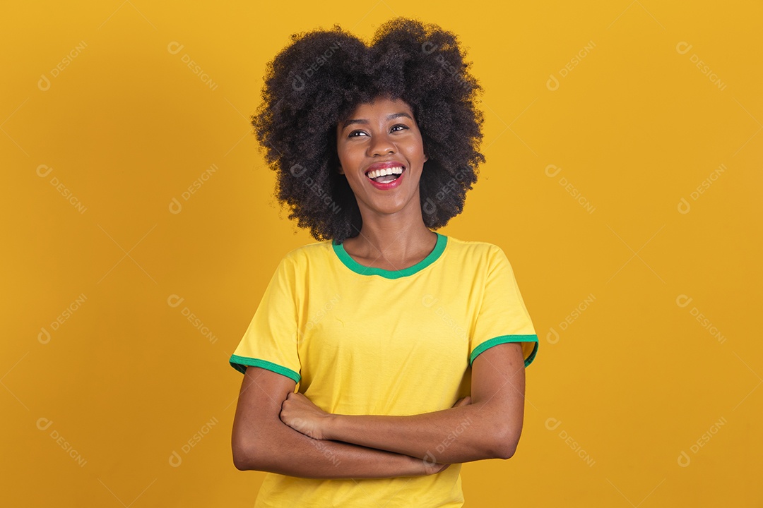 Linda mulher jovem morena torcedora do brasil cabelo afro usando camiseta do brasil sobre fundo isolado amarelo