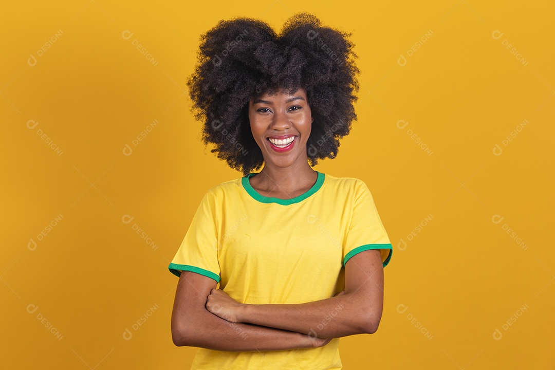 Linda mulher jovem morena torcedora do brasil cabelo afro usando camiseta do brasil sobre fundo isolado amarelo