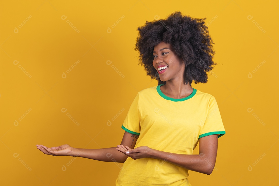 Linda mulher jovem morena torcedora do brasil cabelo afro usando camiseta do brasil sobre fundo isolado amarelo
