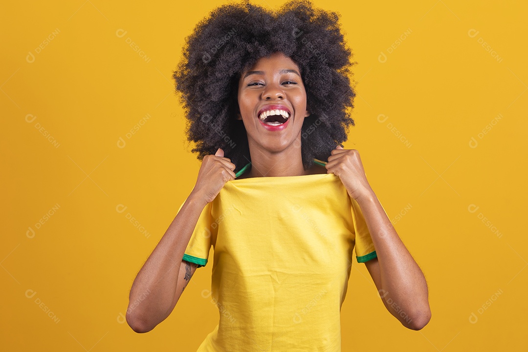 Linda mulher jovem morena torcedora do brasil cabelo afro usando camiseta do brasil sobre fundo isolado amarelo