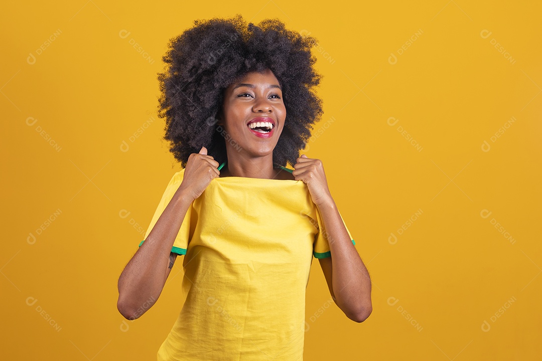 Linda mulher jovem morena torcedora do brasil cabelo afro usando camiseta do brasil sobre fundo isolado amarelo