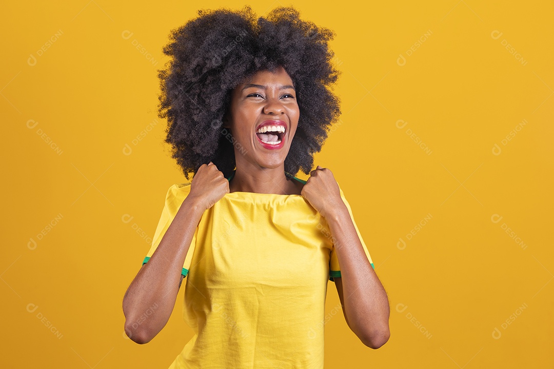 Linda mulher jovem morena torcedora do brasil cabelo afro usando camiseta do brasil sobre fundo isolado amarelo