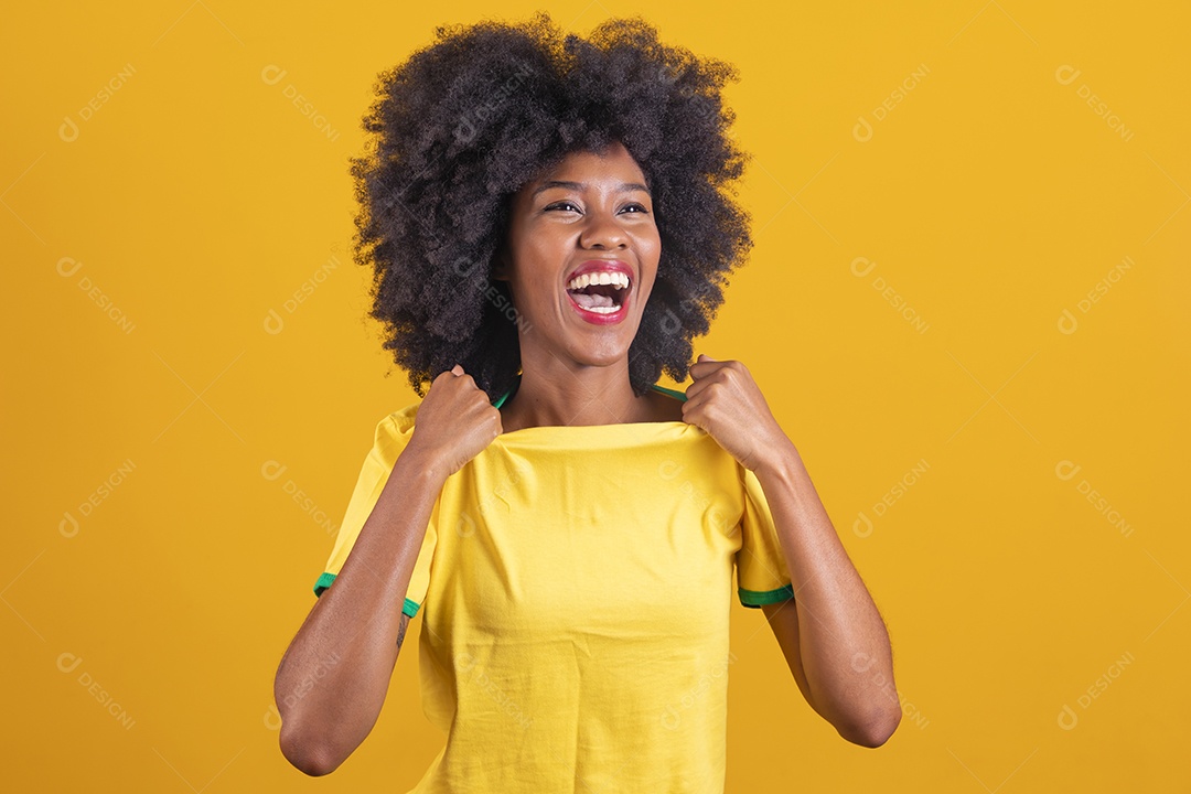 Linda mulher jovem morena torcedora do brasil cabelo afro usando camiseta do brasil sobre fundo isolado amarelo
