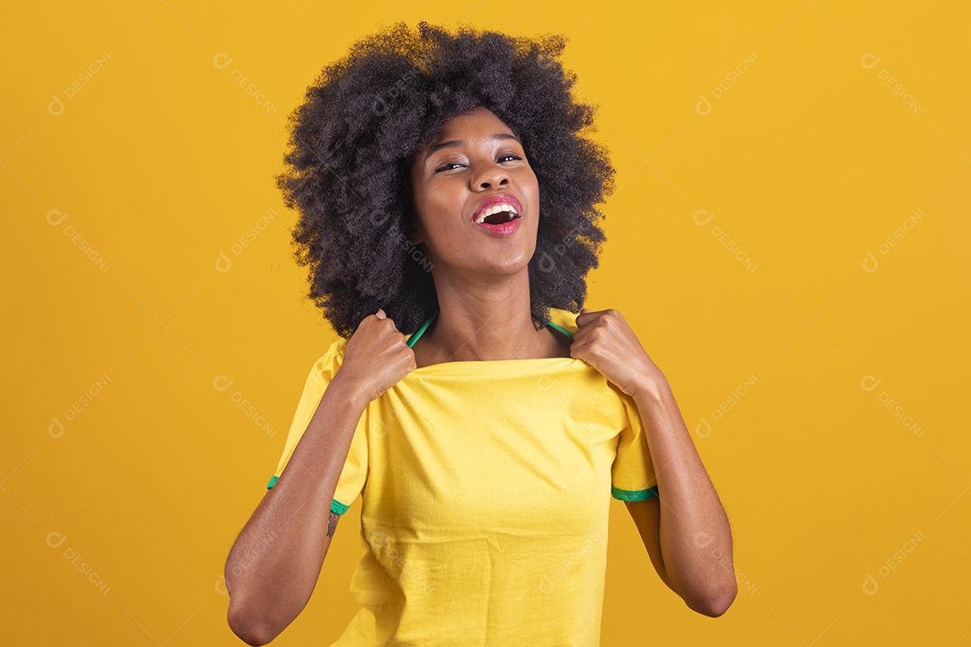 Linda mulher jovem morena torcedora do brasil cabelo afro usando camiseta do brasil sobre fundo isolado amarelo