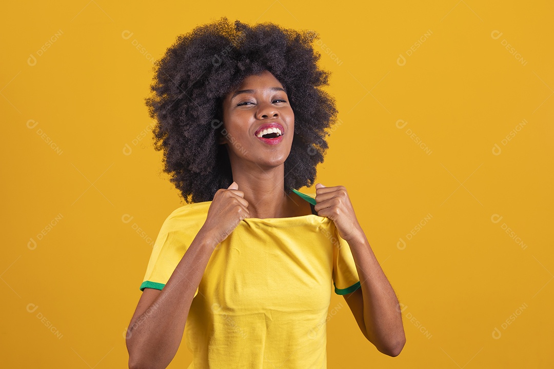 Linda mulher jovem morena torcedora do brasil cabelo afro usando camiseta do brasil sobre fundo isolado amarelo