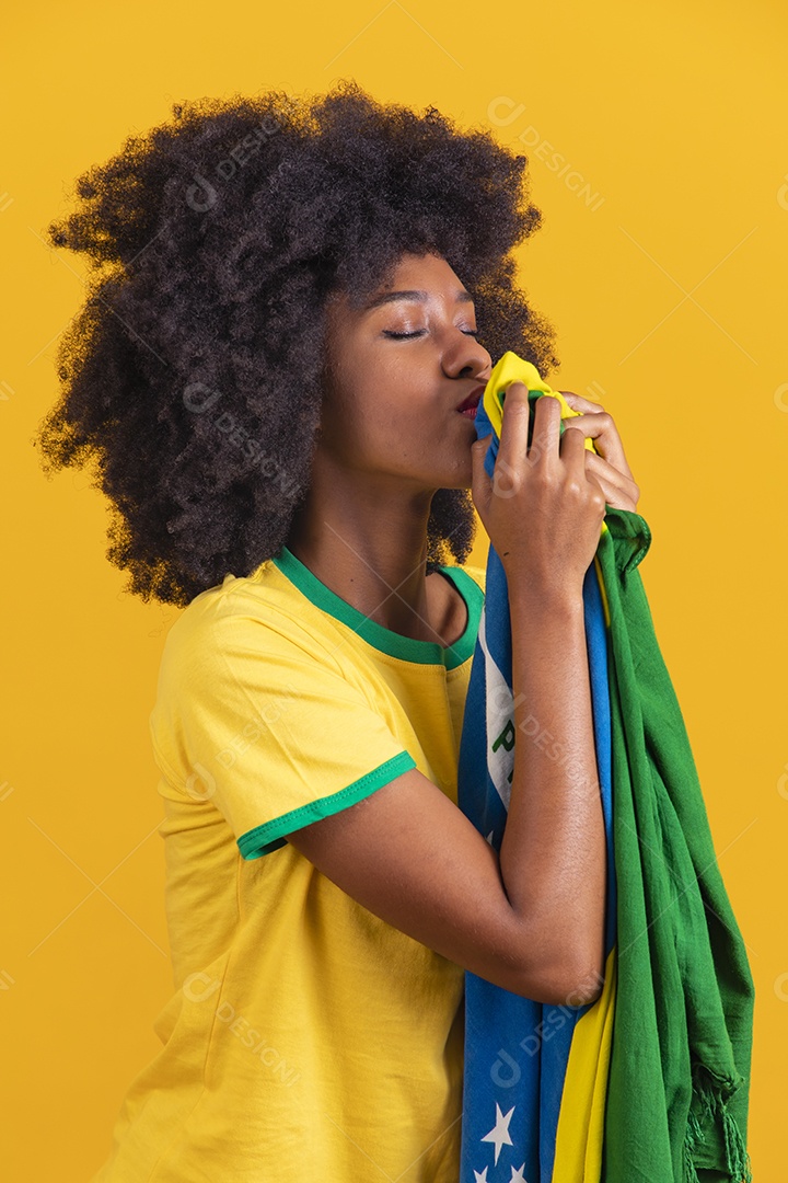 Linda mulher jovem morena torcedora do brasil cabelo afro usando camiseta do brasil sobre fundo isolado amarelo