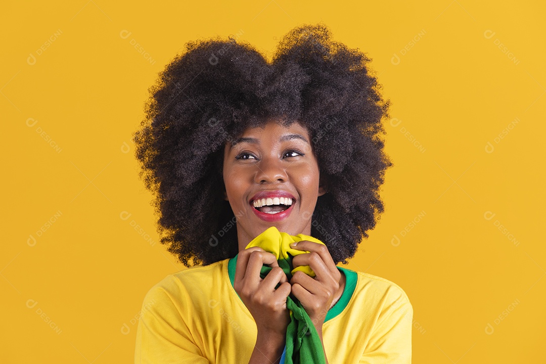 Linda mulher jovem morena torcedora do brasil cabelo afro usando camiseta do brasil sobre fundo isolado amarelo