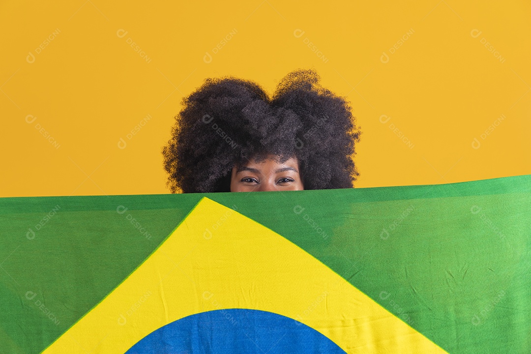Linda mulher jovem morena segurando bandeira do brasil cabelo afro sobre fundo isolado amarelo