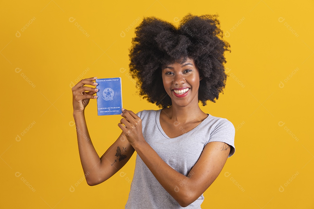 Mulher negra sorridente usando uma camiseta cinza e segurando uma carteira de trabalho