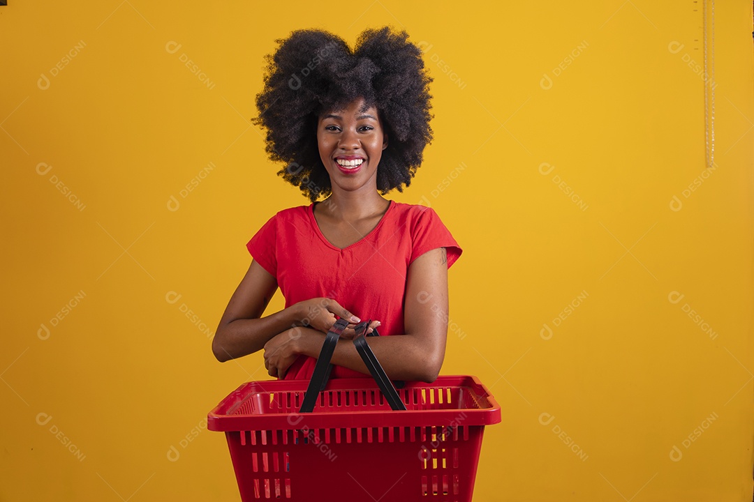 Mulher negra sorridente usando uma camiseta vermelha e segurando uma cesta de compras