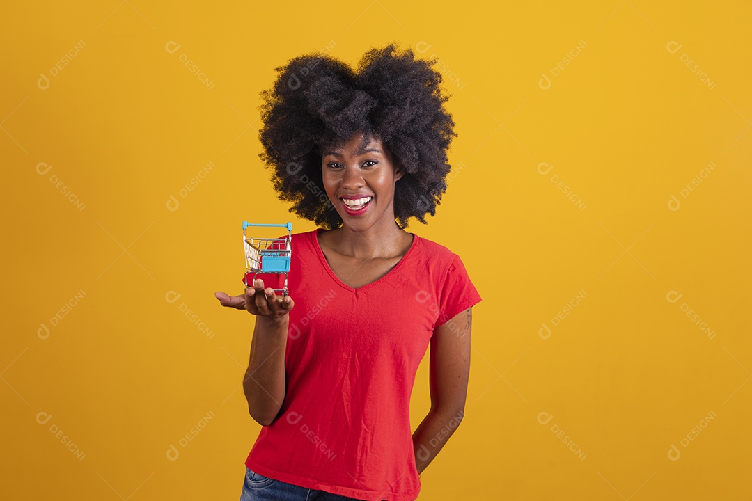 Mulher negra sorridente usando uma camiseta vermelha e segurando um carrinho de compras