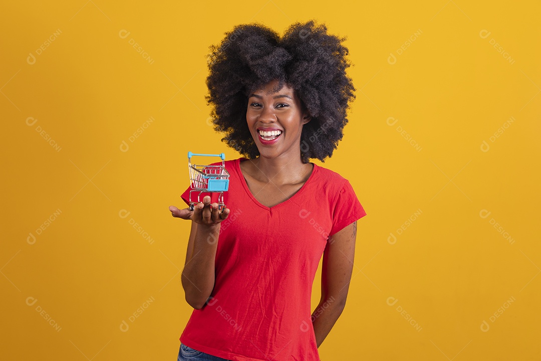 Mulher negra sorridente usando uma camiseta vermelha e segurando um carrinho de compras