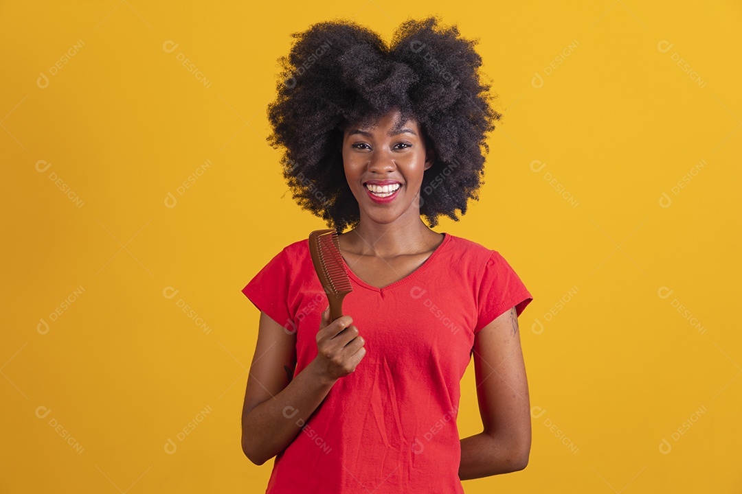 Mulher negra sorridente usando uma camiseta vermelha e segurando um pente