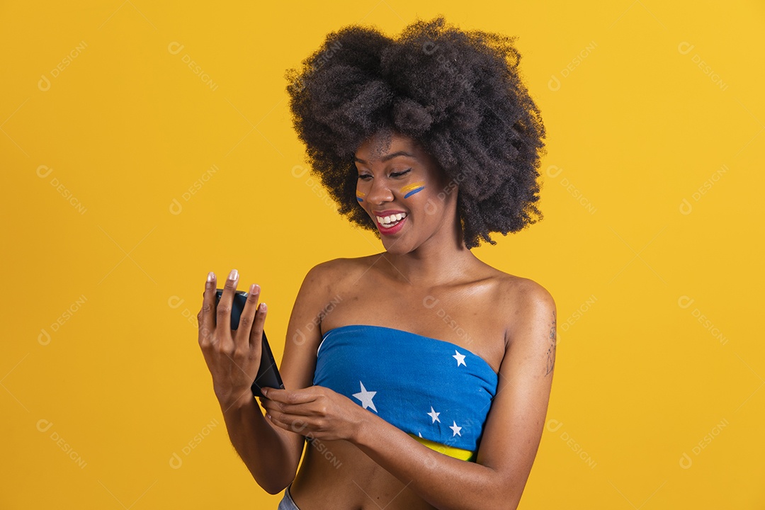 Mulher negra vestindo bandeira do Brasil segurando um smartphone celular