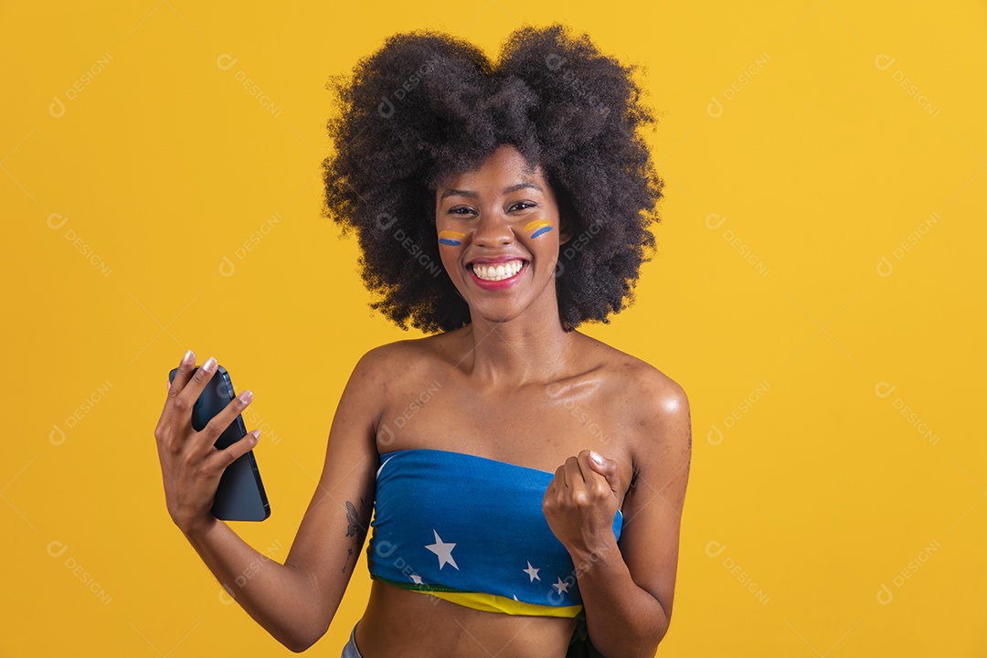 Mulher negra vestindo bandeira do Brasil segurando um smartphone celular