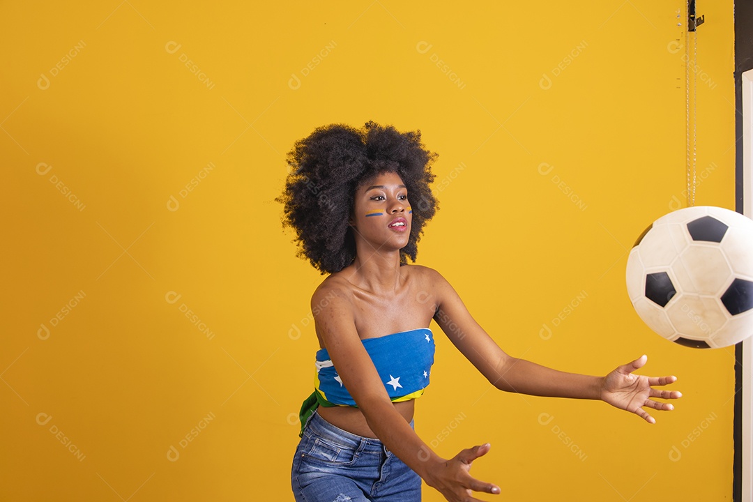 Mulher negra vestindo bandeira do Brasil e jogando bola