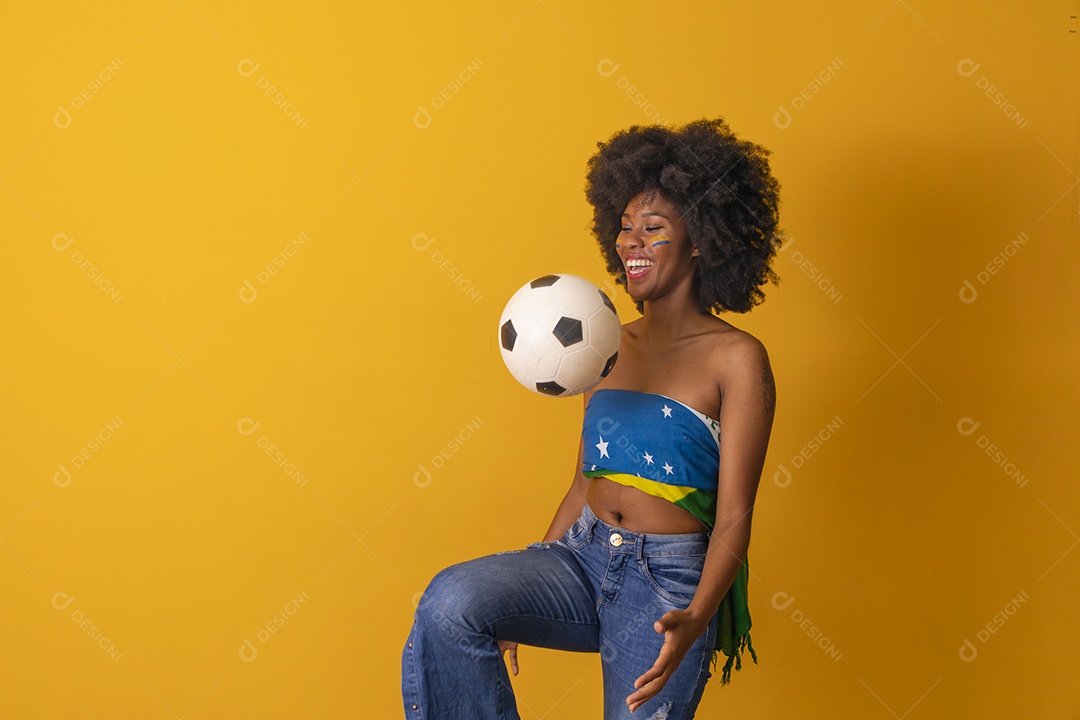 Mulher negra vestindo bandeira do Brasil e jogando bola