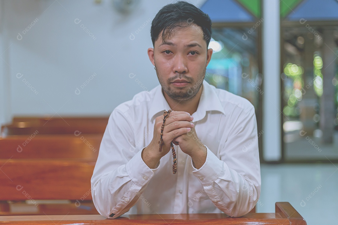 Homem fazendo oração sobre uma igreja católica