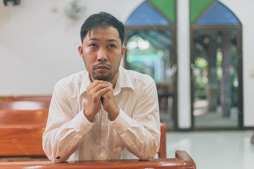 Homem fazendo oração sobre uma igreja católica