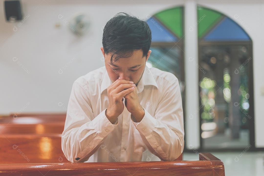 Homem fazendo oração sobre uma igreja católica