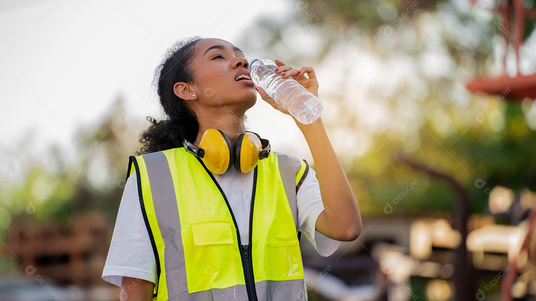 Divergente Um capataz ou trabalhadora afro-americana usando segurança Cross Eye está bebendo uma garrafa de água depois de terminar o trabalho