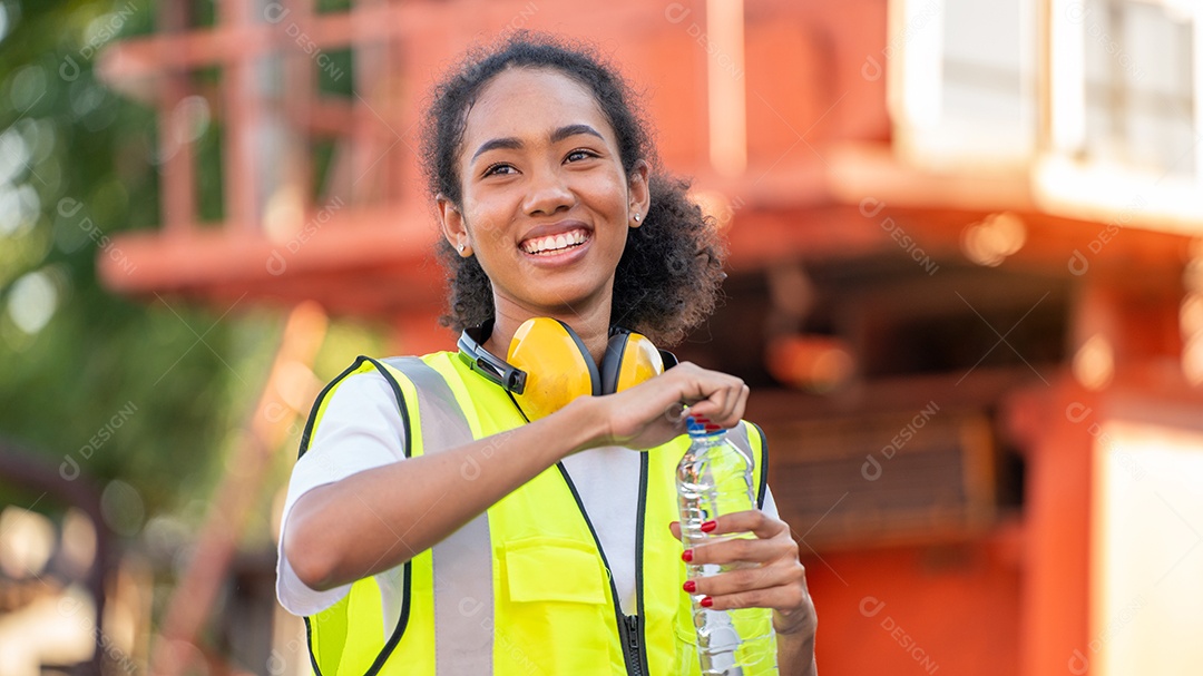 Divergente Um capataz ou trabalhadora afro-americana usando segurança Cross Eye está bebendo uma garrafa de água depois de terminar o trabalho
