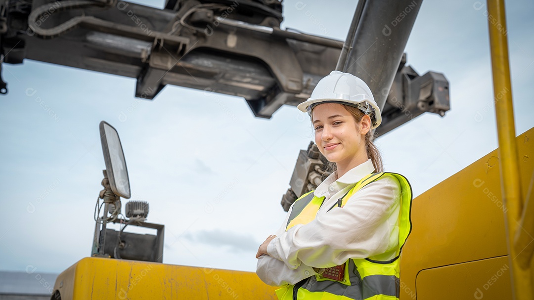 O contramestre da mulher sorri ao lado da empilhadeira de carga no armazém