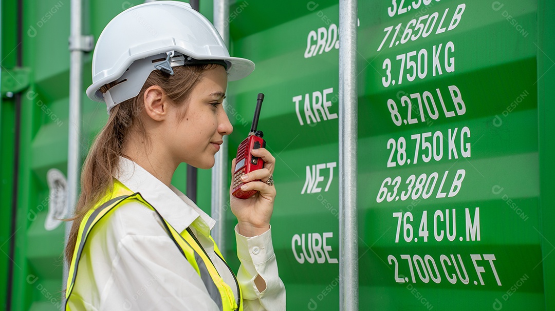 Mulher capataz sorri ao lado do contêiner de carga no armazém, gerente no capacete branco Supervisora