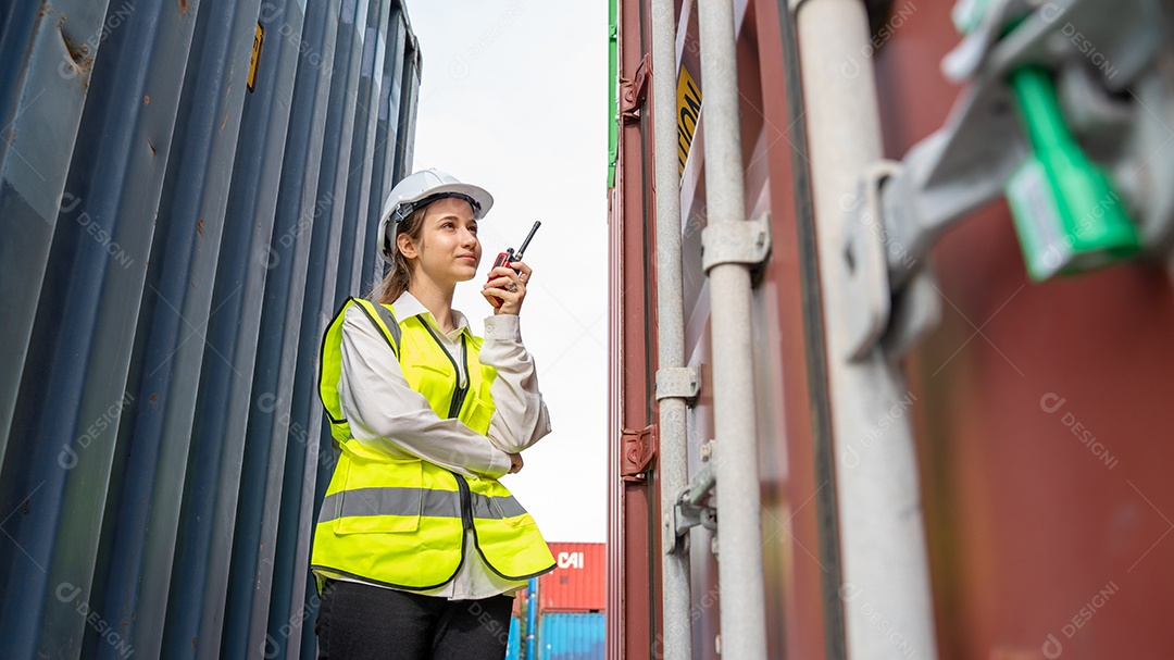 Mulher capataz sorri ao lado do contêiner de carga no armazém, gerente no capacete branco Supervisora