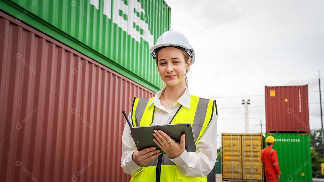 Mulher capataz sorri ao lado da empilhadeira de carga no armazém, gerente usa tablet no capacete branco Supervisor de segurança no conceito de porta do terminal personalizado de contêiner importação exportação