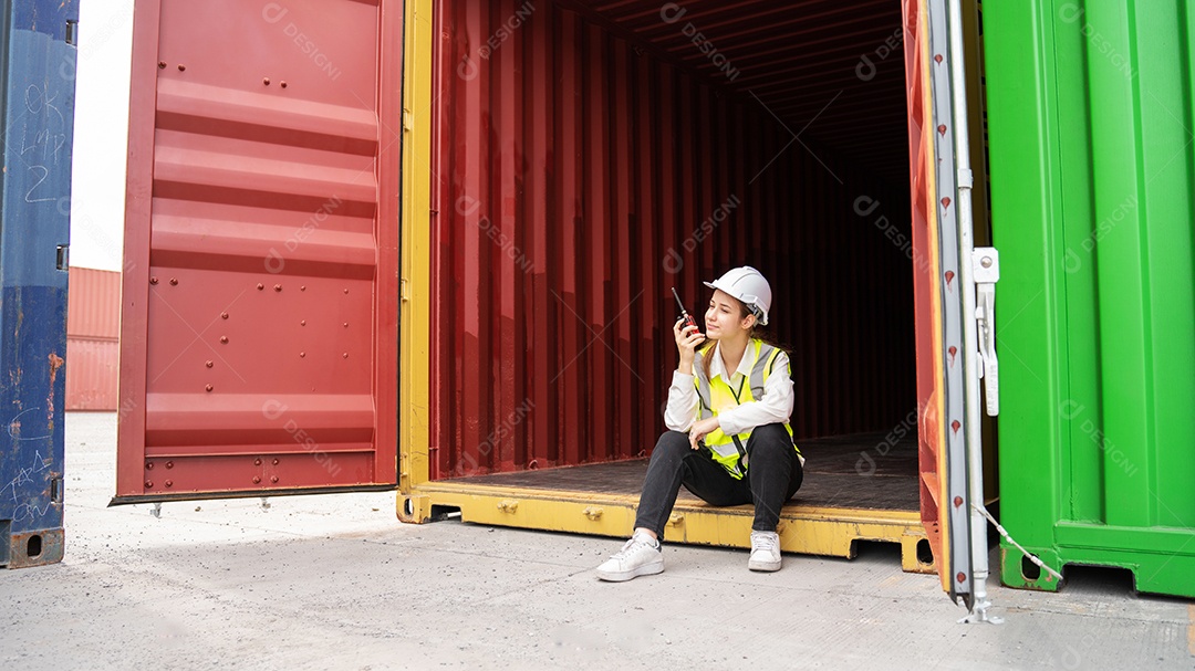 O sorriso do capataz feminino senta-se dentro do contêiner de carga no armazém, supervisor de segurança do gerente no conceito de porta do terminal personalizado de contêiner importação exportação
