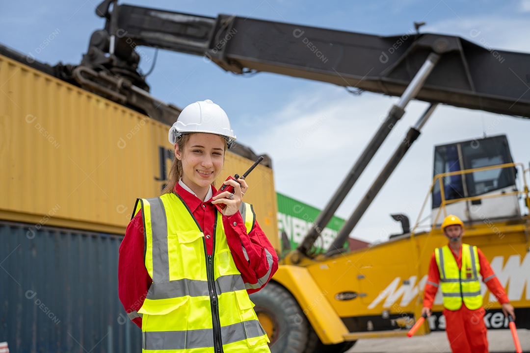 Mulher capataz sorria usando walkie talkie na frente do garfo de carga.