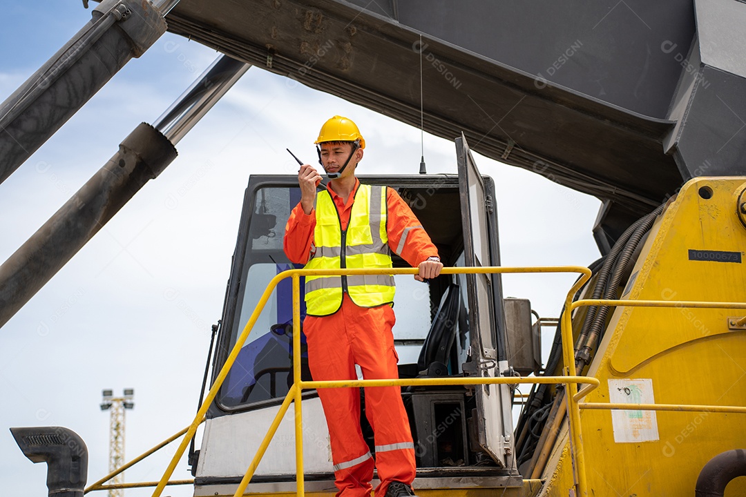 Sorriso de capataz usando walkie talkie na frente da empilhadeira de carga.