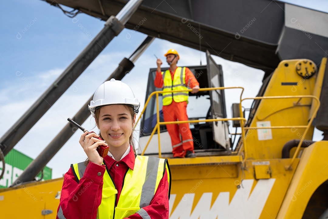 Mulher capataz sorria usando walkie talkie na frente do garfo de carga.