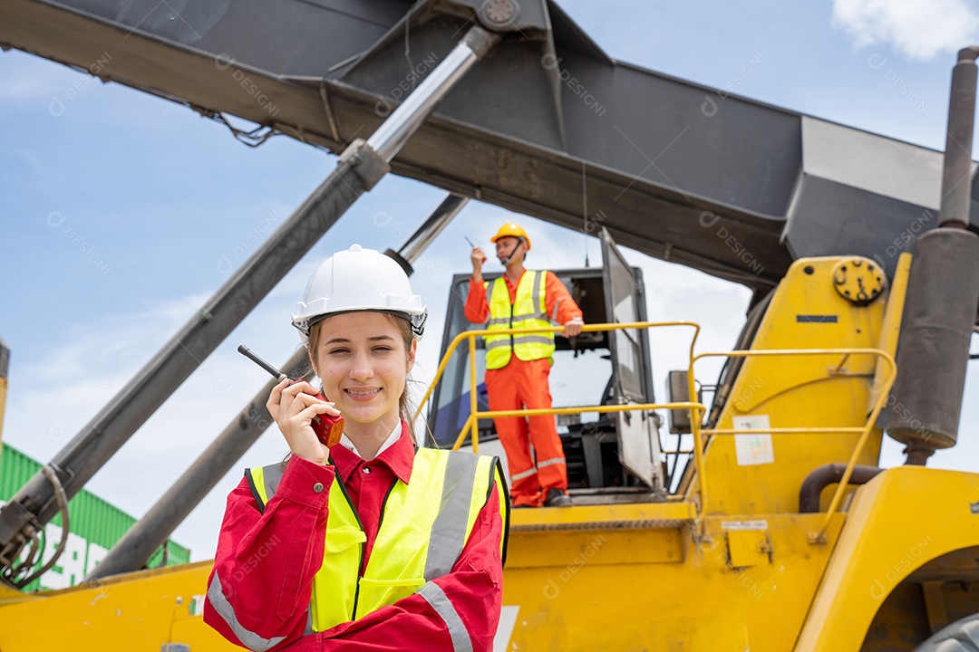 Mulher capataz sorria usando walkie talkie na frente do garfo de carga.