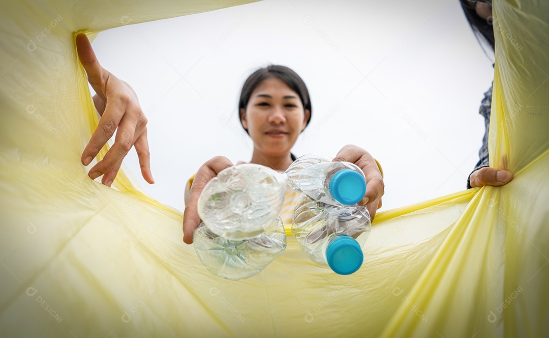 Mulher joga lixo de plástico em um lixo.