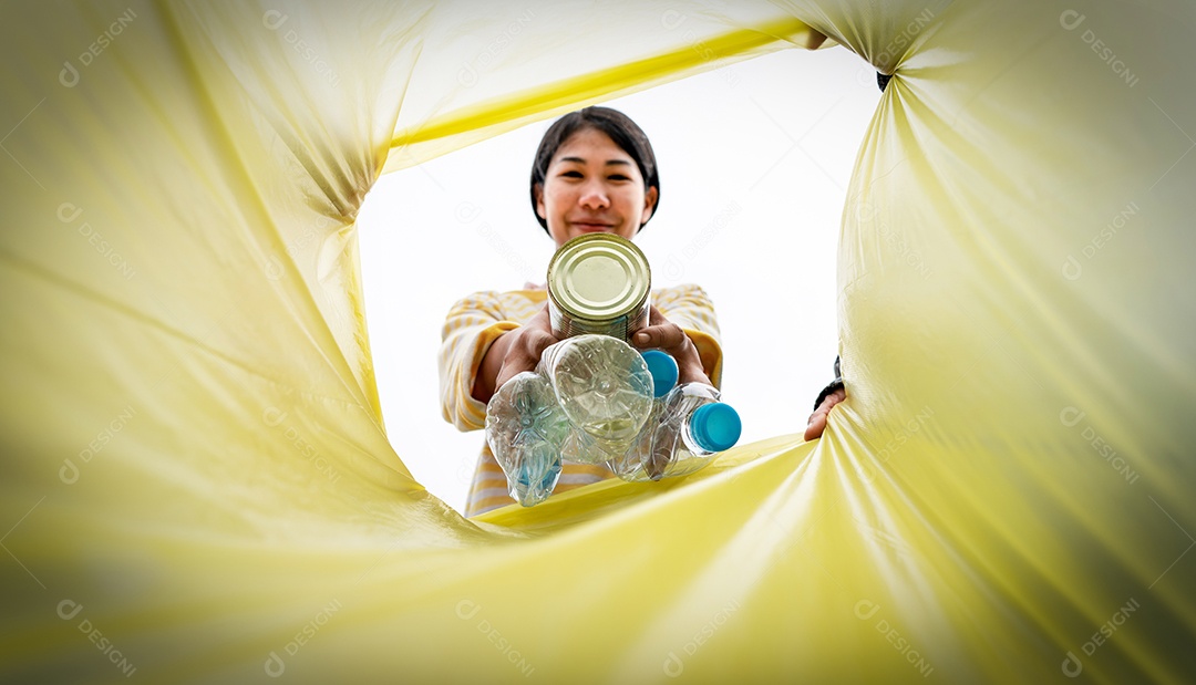 Mulher joga lixo de plástico em um lixo.