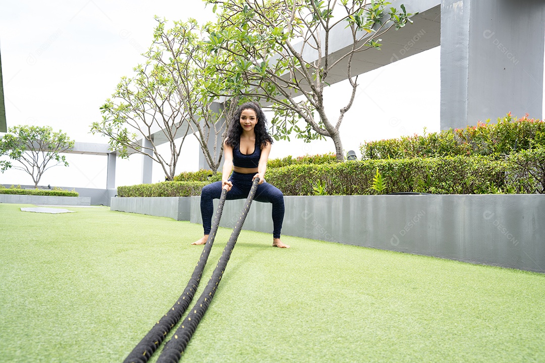 Mulher fazendo treino de corda de batalha no telhado do condomínio.