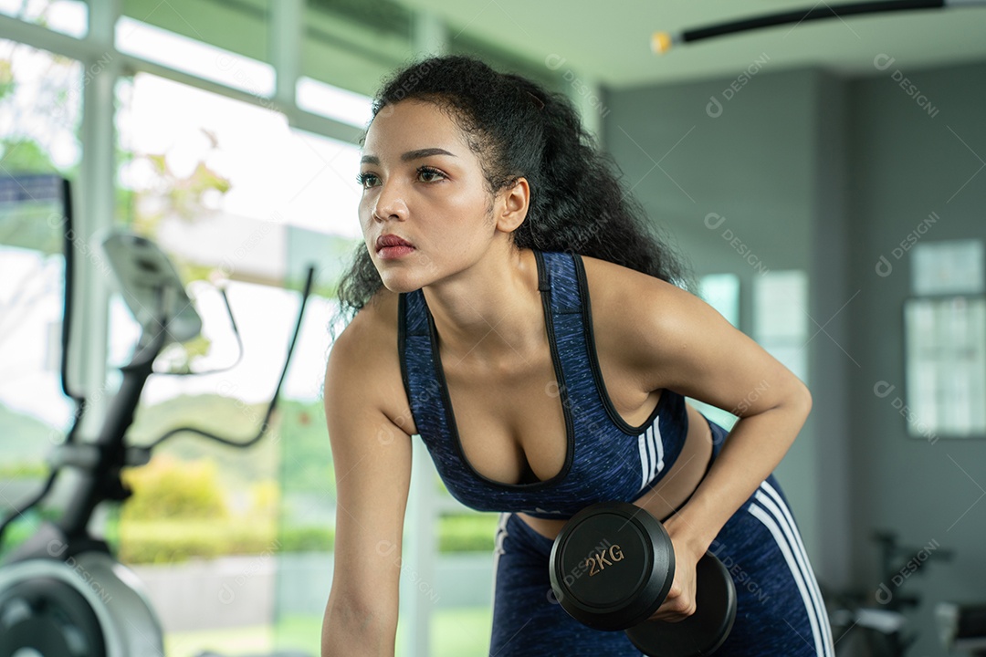 Linda jovem musculação com halteres no ginásio.