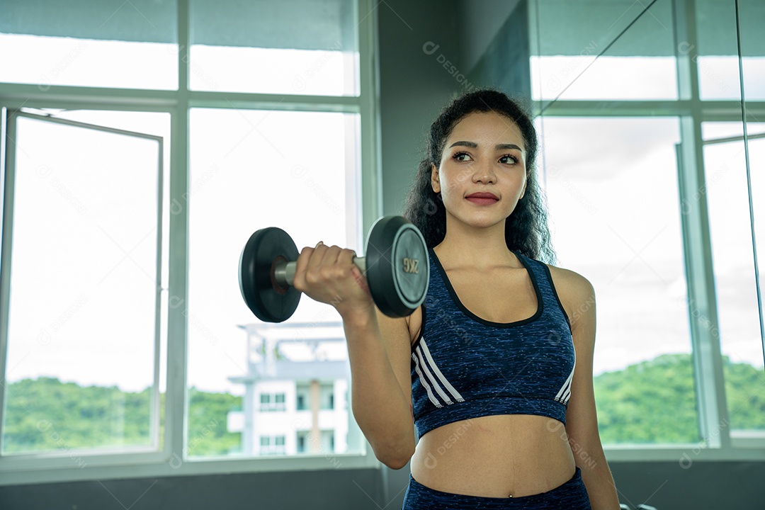 Linda jovem musculação com halteres no ginásio.