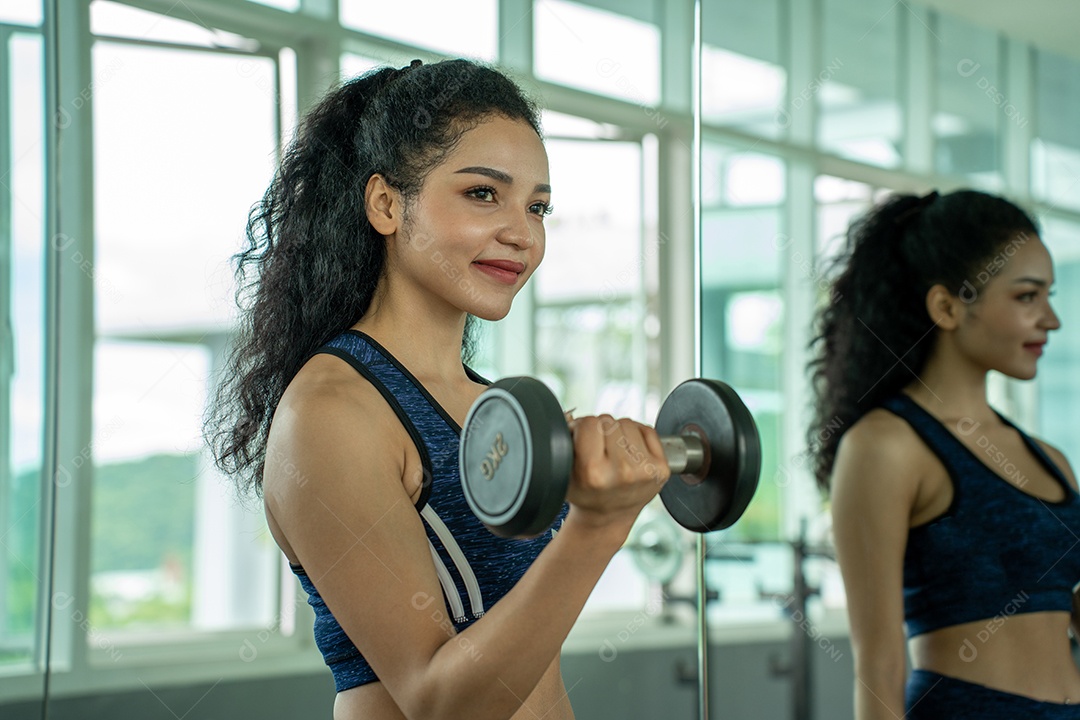 Linda jovem musculação com halteres no ginásio.