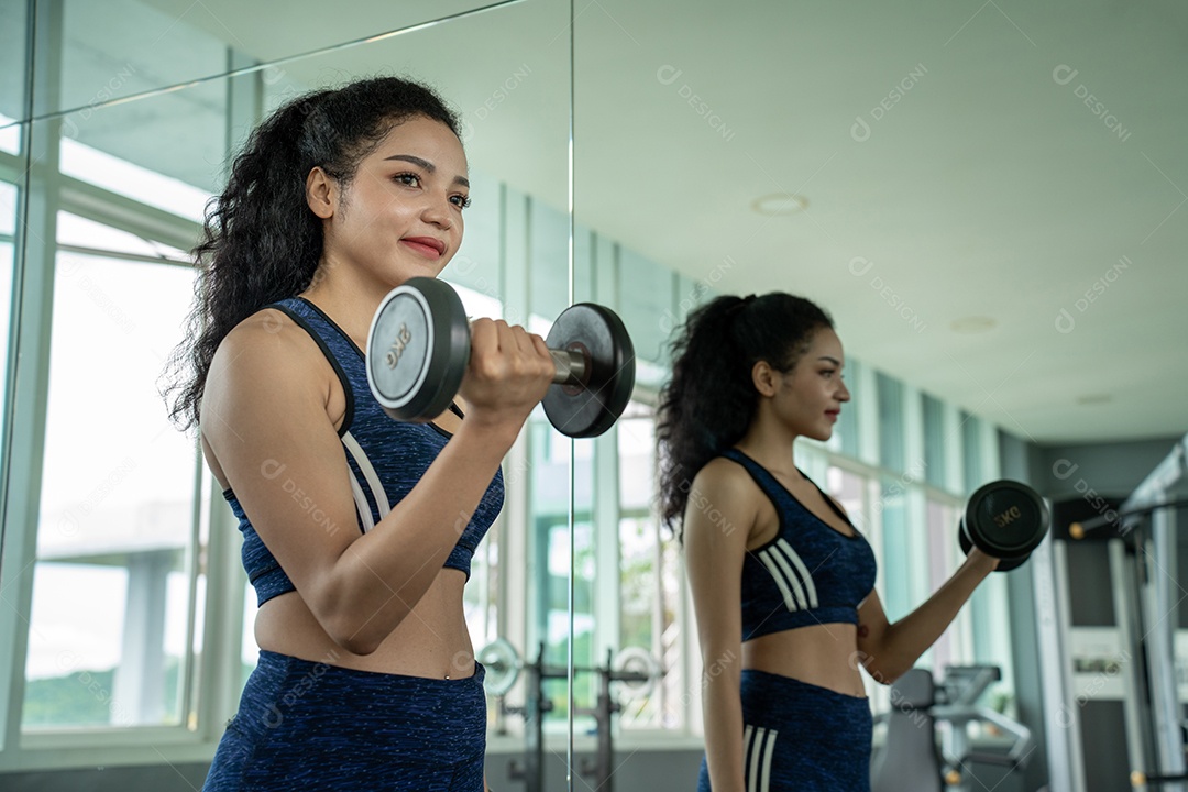 Linda jovem musculação com halteres no ginásio.