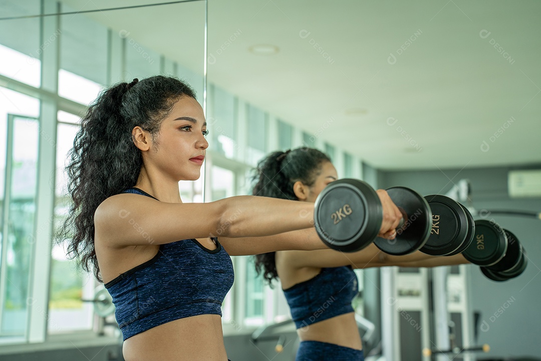 Linda jovem musculação com halteres no ginásio.