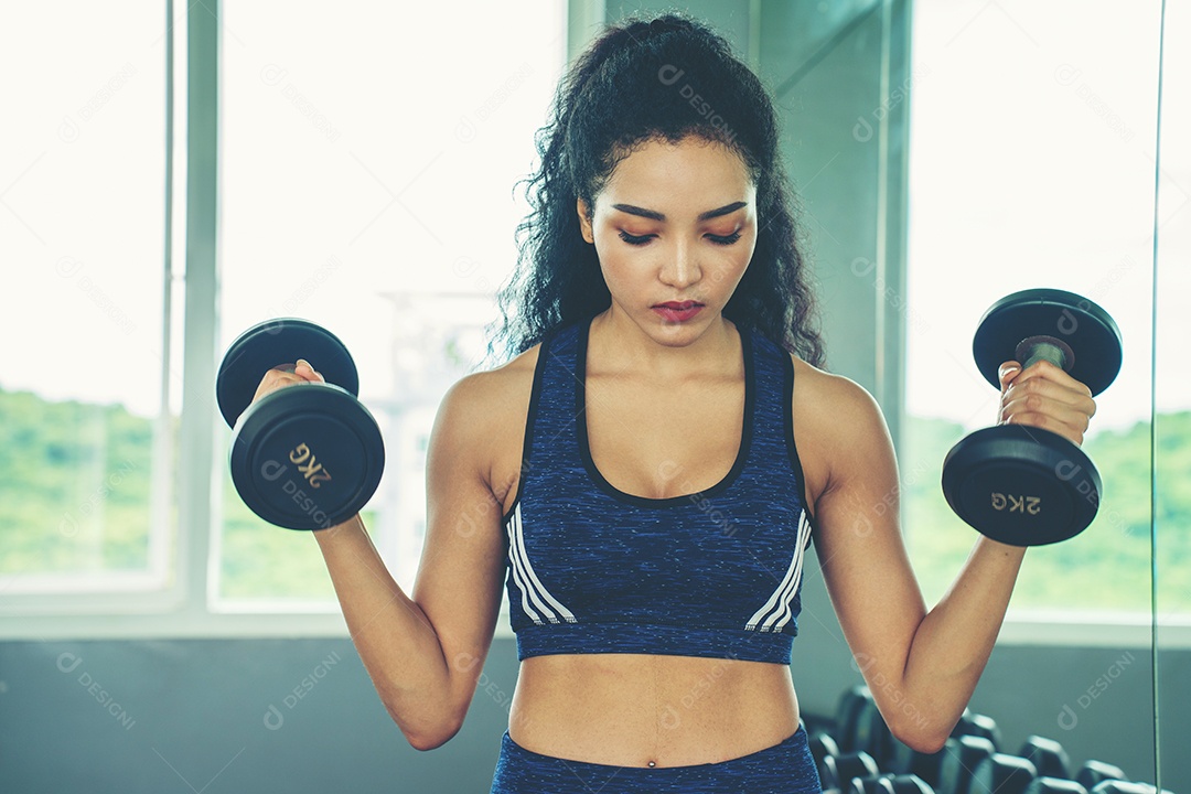 Linda jovem musculação com halteres no ginásio.