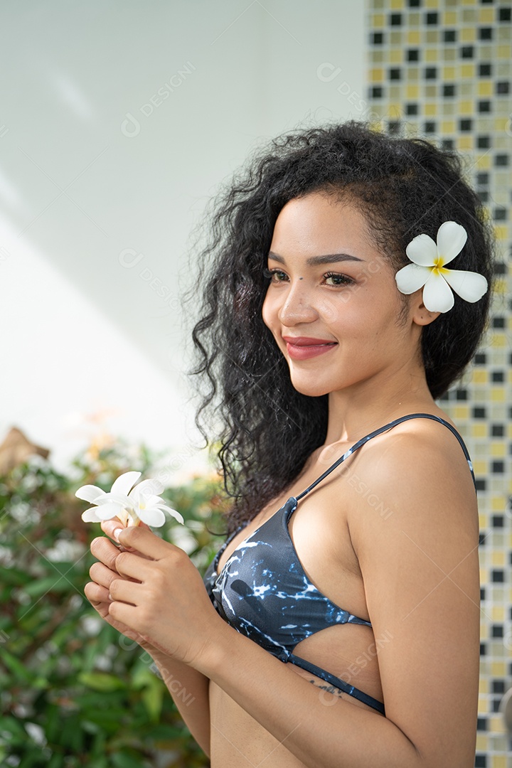 Corpo bronzeado magro de jovem em biquíni em folhas de palmeira.