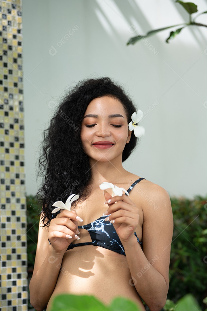 Corpo bronzeado magro de jovem em biquíni em folhas de palmeira.